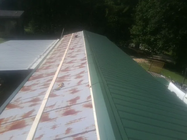 Old rusted panels beside newly installed green metal roofing — Wind Damage Roof Repair by Roofing Brothers in Windsor